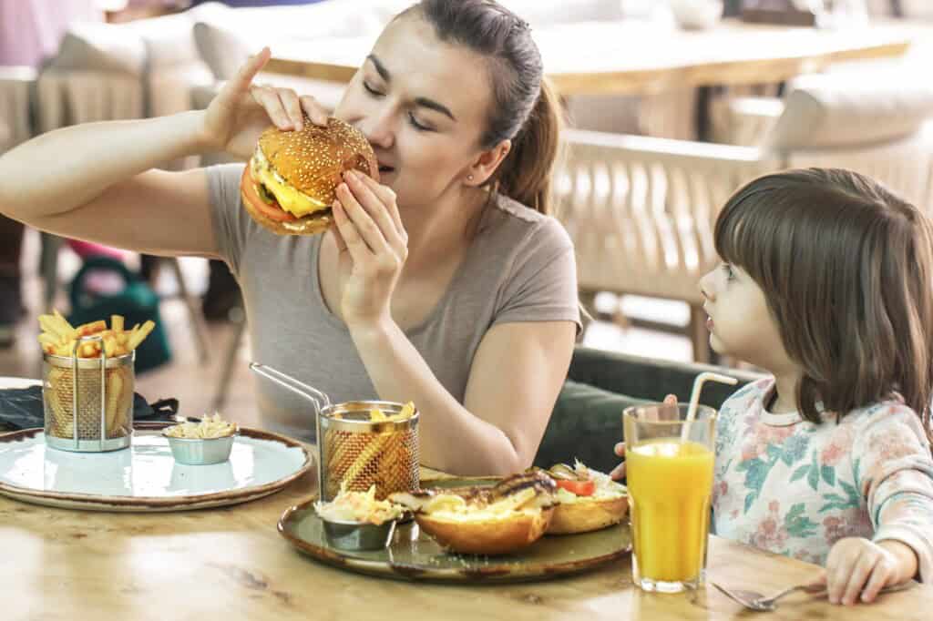 Mother and daughter eating burgers and chips in a restaurant