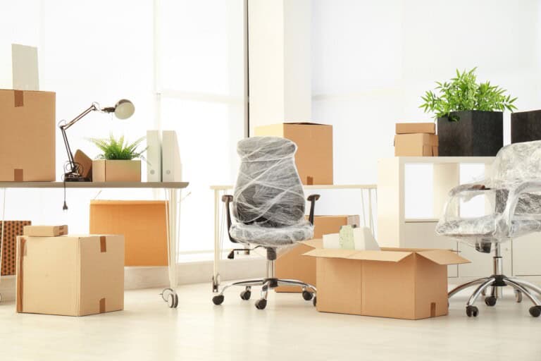 Moving boxes and office furniture in the concept of 'How to communicate an office move to clients and partners'.