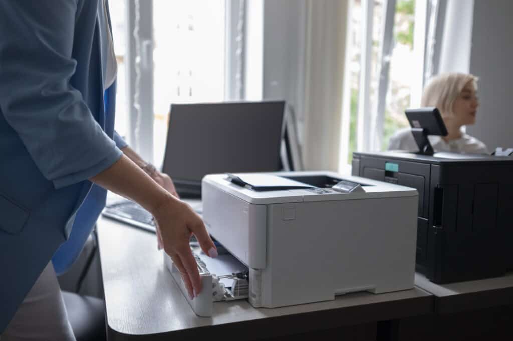 Cropped image of a woman using a printer beside a scanner and desktop