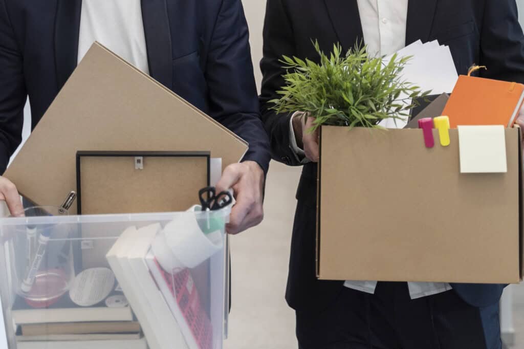 Cropped image of male employees carrying boxes of their office items to set up at the new office